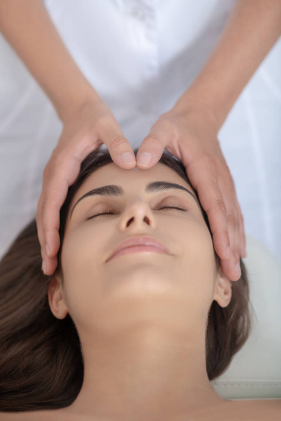 Professional massage therapist putting hands on customers head - Fotografie, Obrázek
