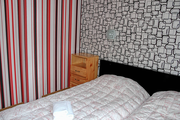 υπνοδωμάτιο εσωτερικό σε ξύλινο εξοχικό σπίτι, ξύλινο κομοδίνο και close-up του κρεβατιού με απαλή λευκή κουβέρτα - Φωτογραφία, εικόνα