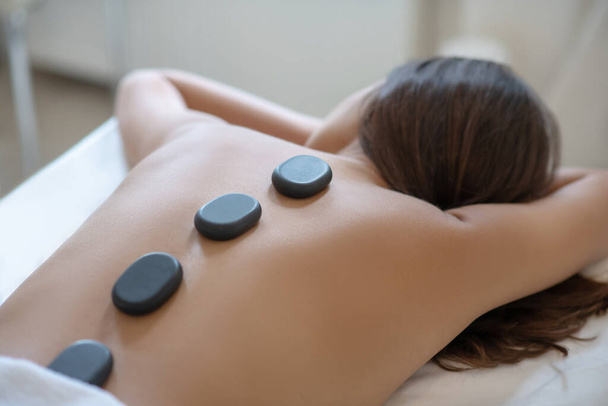 Dark-haired woman lying on the couch and having hot stone therapy - Фото, зображення
