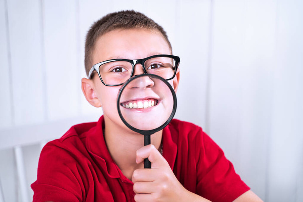 小さな男の子は虫眼鏡を通して肯定的で否定的な感情を表現します。学校に戻りなさい。感情を表現する方法を教育する - 写真・画像