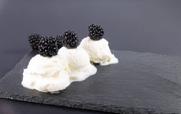 Brombeeren und weißes Eis auf schwarzem Hintergrund. Natürliche frische Brombeeren aus dem Garten. Schnelles Dessert-Rezept. - Foto, Bild