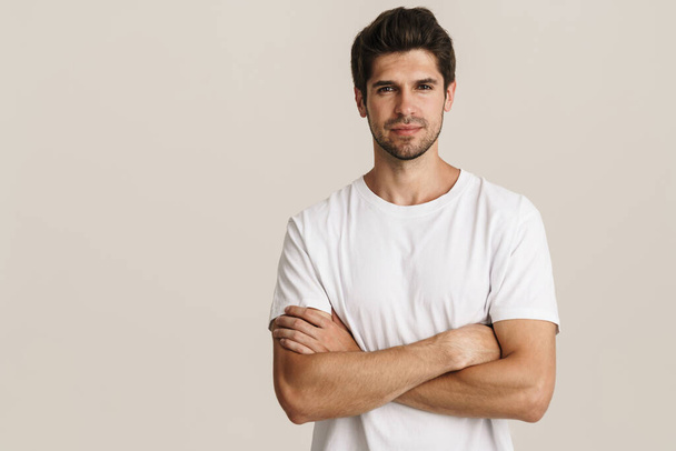Image of confident young man posing on camera with arms crossed isolated by white background - Foto, Imagen