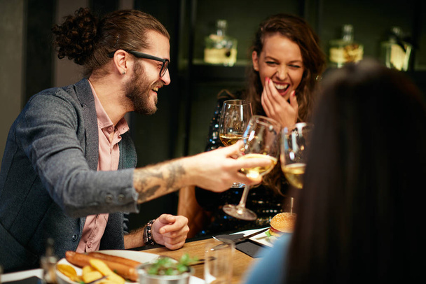 Grupo de amigos em um restaurante, jantar e brindar com vinho branco. - Foto, Imagem