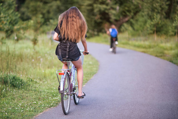 A girl riding a bicycle in a park in summer in the sunny morning. - Foto, Imagen