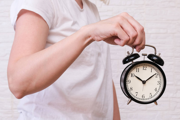 Woman holding an alarm clock showing 10 oclock, people should value and appreciate time, deadline concept - Photo, image