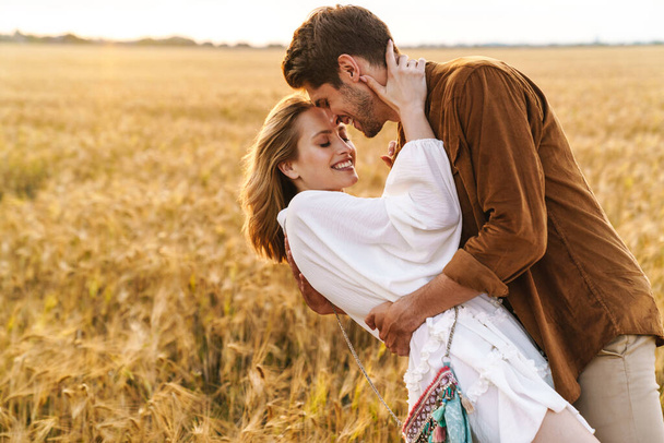 Image of young caucasian beautiful couple hugging together in golden field on countryside - Foto, immagini