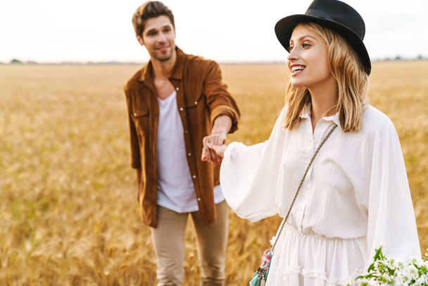 Image of young caucasian beautiful couple walking together in golden field on countryside - Φωτογραφία, εικόνα
