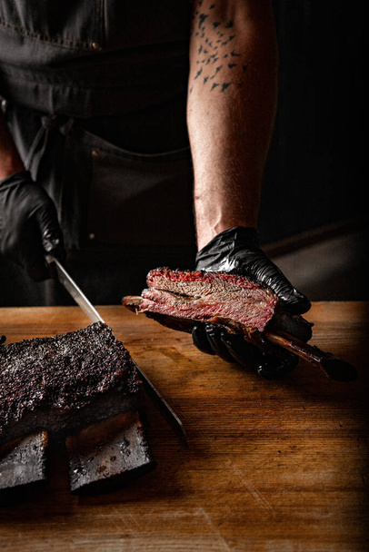 Chef slicing brisket beef on cutting board in kitchen - Фото, зображення