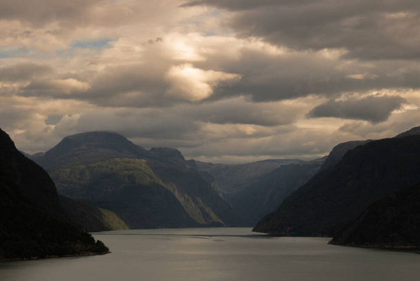 Paisaje que muestra el fiordo de Aurlandsfjord entre montañas y bajo un cielo nublado en Noruega - Foto, imagen