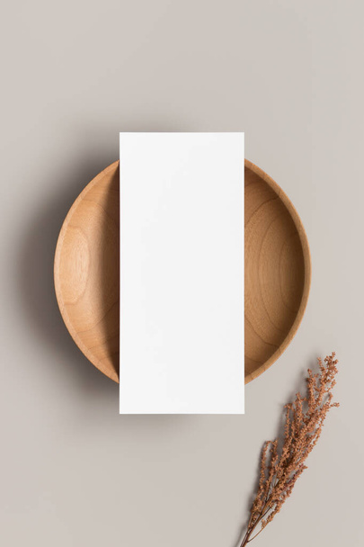 Макет картки меню на дерев'яній тарілці з сухою квіткою, співвідношення 4x9
. - Фото, зображення