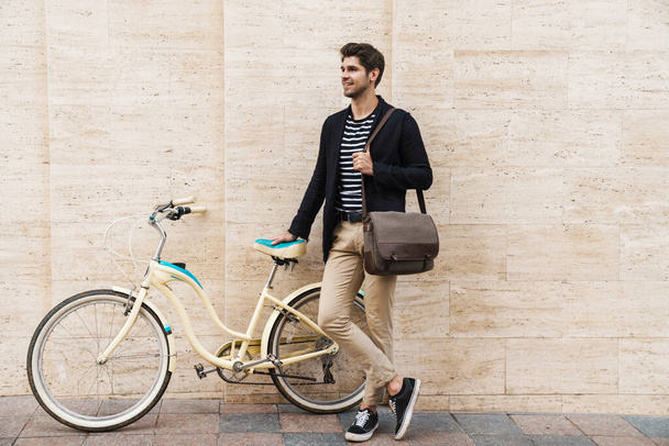 Photo of a young cheerful handsome young business man outdoors on a bicycle - Fotoğraf, Görsel