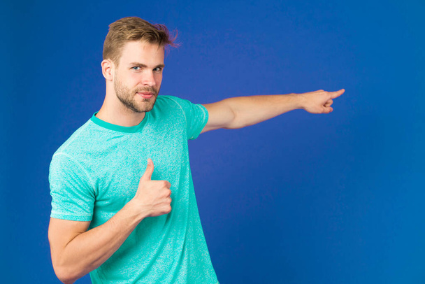 Highly recommend pointing at with index finger. Man unshaven face shows thumbs up gesture violet background. Man satisfied face recommend show right direction. Guy approve that direction - Foto, imagen