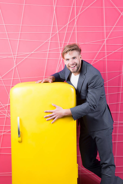 Man formal elegant suit stand near retro vintage yellow refrigerator. Vintage household appliances. Bachelor hungry guy think what eat near fridge. Bright fridge household appliances interior object - Foto, Imagen