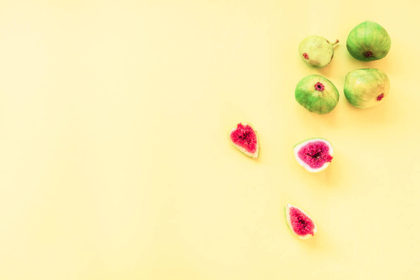 Whole green figs and sliced on a yellow background, flat lay, copy space - Foto, Imagen