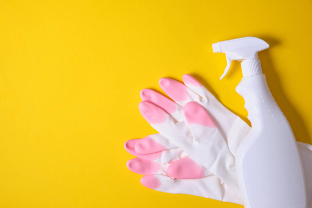Set of cleaning supplies on blue background. Flat lay yellow rag and sponge, rubber gloves, cleaner spray bottle, detergent. House cleaning service and housekeeping concept - 写真・画像