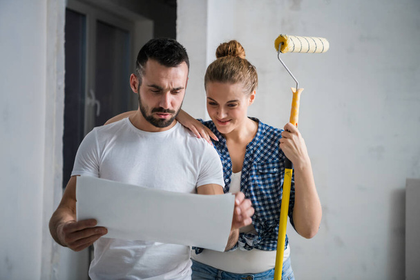 Man and his girlfriend holding house plan in hands and smiling - Foto, Bild