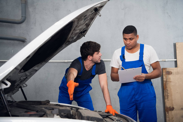 Workshop worker consults with a colleague about a car - Foto, afbeelding