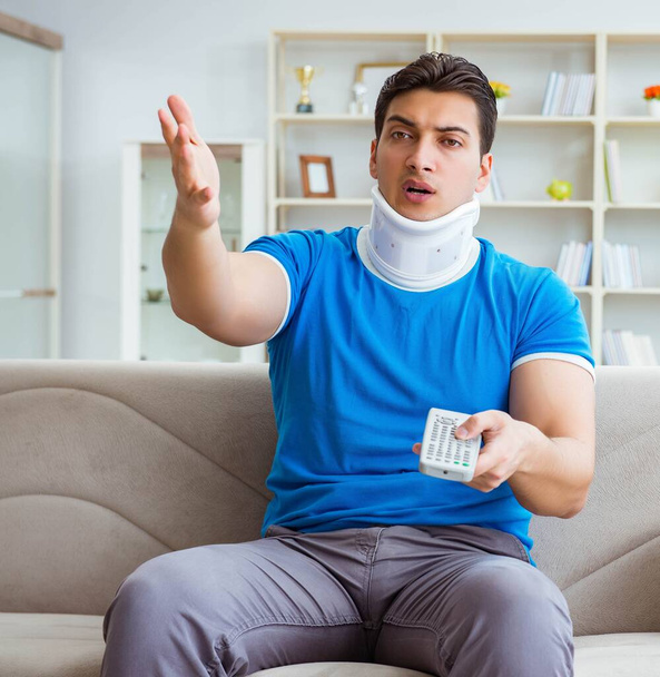 Homem com lesão no pescoço assistindo futebol em casa - Foto, Imagem