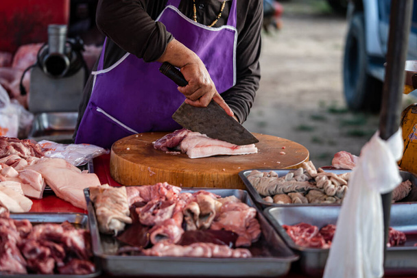 Imagen de un comerciante de carne Utilice un cuchillo para cortar cerdo en una tabla de cortar de madera para vender en los mercados rurales. - Foto, Imagen