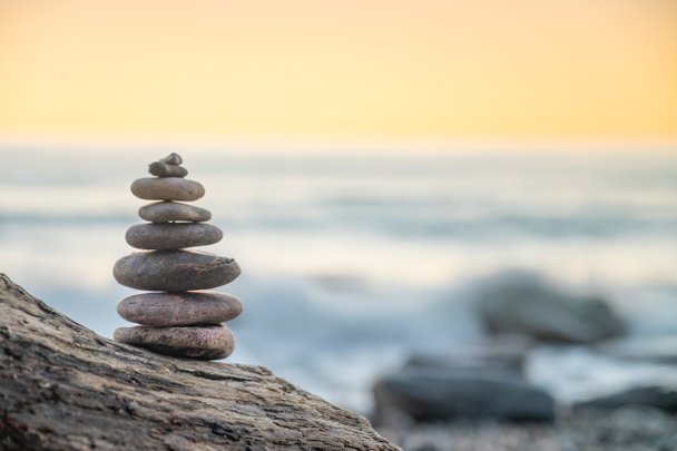 Zen balanced stones stacked on sea coast at sunset. Balance and equilibrium concept. - Photo, Image