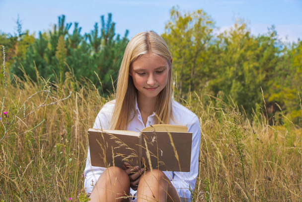 beautiful girl in nature reads an interesting book in summer and autumn. - Φωτογραφία, εικόνα