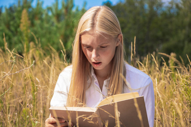 beaubeautiful girl in nature reads an interesting book in summer and autumn. - Fotoğraf, Görsel