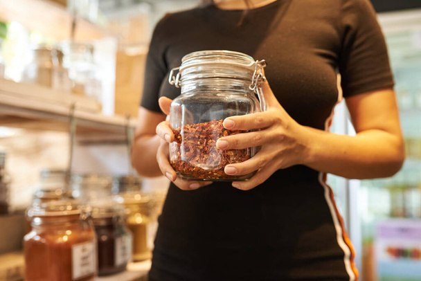 Zero waste food shopping. Hands with grocery products in reusable glass jars. Woman buying bulk dry goods in sustainable plastic free store. Eco-friendly low waste concept. Minimalist lifestyle - Photo, Image