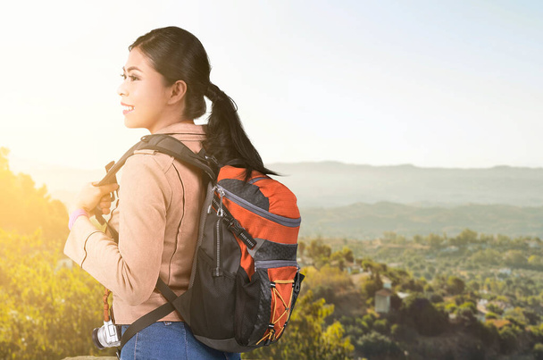 Asian woman with a backpack with a mountain view and blue sky background. World Tourism Day. - Foto, immagini