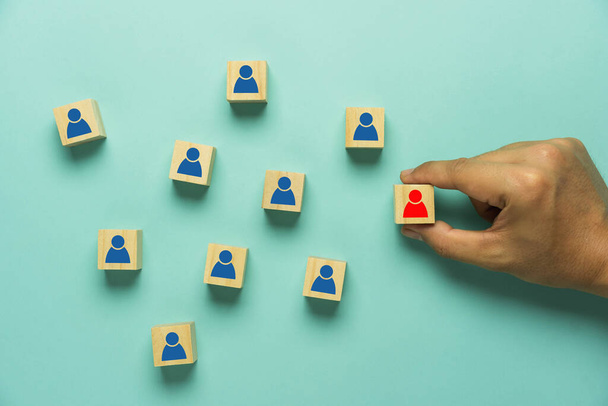 Top view of human resources and recruiting business or team leader concepts. Hand adult Asian man holding difference of people icon on triangle wooden block. Objects on blue paper background. - Foto, Bild