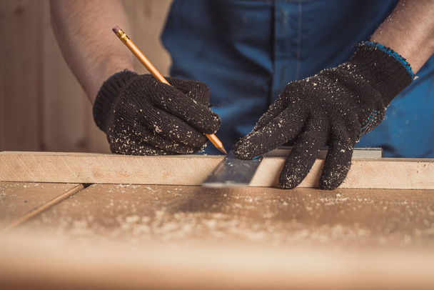 CLose up of the carpenter with a pencil and tape measure mark on wooden board on table. Construction industry, housework do it yoursel. Work with wooden - Foto, Imagem