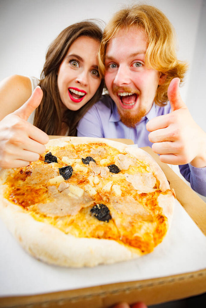 Funny crazy man and woman spending time together. Cheerful couple or friends eating delicious cheesy pizza. - Foto, immagini