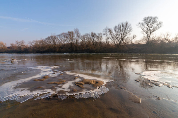 Fredda giornata invernale mattutina, su una sponda selvaggia del fiume, con gelo e neve - Foto, immagini