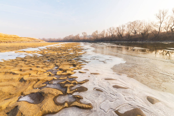 Día frío de invierno por la mañana, en la orilla de un río salvaje, con heladas y nieve - Foto, imagen