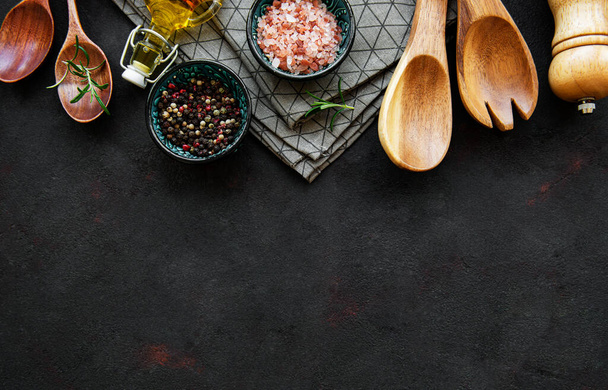 Old wooden kitchen utensils and spices as a border on a black background - Φωτογραφία, εικόνα