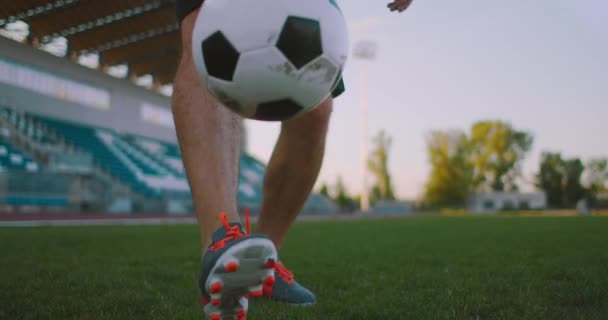 Profesyonel futbol ligindeki ağır çekimde, güneşli bir yaz gününde sahada top bacağında hokkabazlık yapan erkek. - Video, Çekim