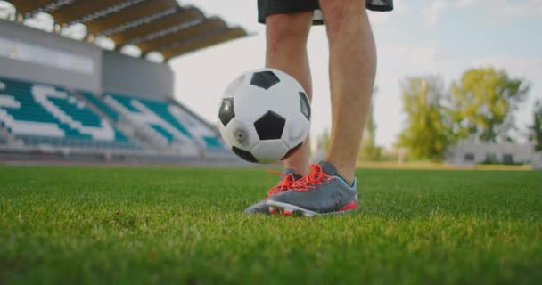 Futbol sahasında ağır çekimde spor aletleriyle zıplayan bir adam futbol topunu sektirir. - Video, Çekim