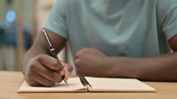 close-up van Afrikaanse man schrijven in notebook - Video