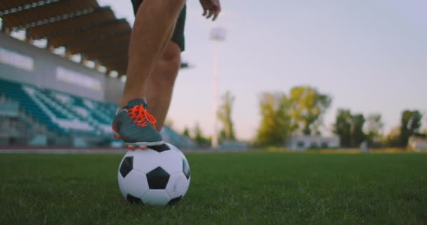 Przechyl się w zwolnionym tempie samca z profesjonalnej ligi piłki nożnej żonglerka piłkę na nodze w polu gry na świeżym powietrzu w słoneczny letni dzień - Materiał filmowy, wideo