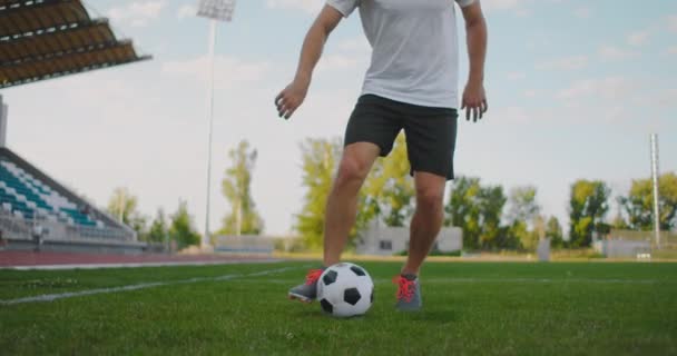 競技場のサッカー選手は、走りながら剣をリードしながらサッカーボールでドリブルを実証します。サッカー選手とボールコントロールの優れたスキル - 映像、動画