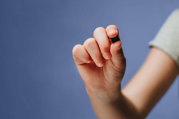 Une fille tient dans sa main et examine une petite puce noire. Chipisation de personnes après un coronavirus épidémique. Espace de copie - Photo, image