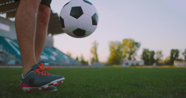 Нахилитися з повільним рухом чоловіків з професійної футбольної ліги жонглювання м'яч на нозі на відкритому повітрі граючи поле в сонячний літній день
 - Кадри, відео