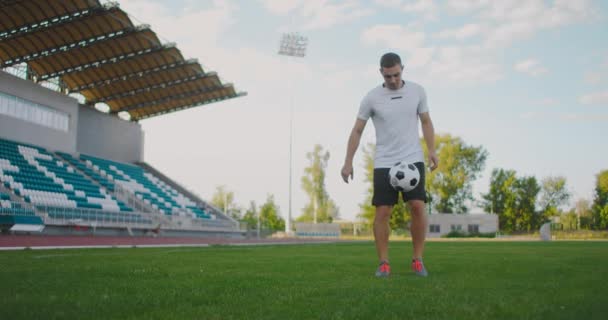 Atleta profissional jogador de futebol masculino no campo de futebol em câmera lenta em equipamentos esportivos saltar uma bola de futebol - Filmagem, Vídeo