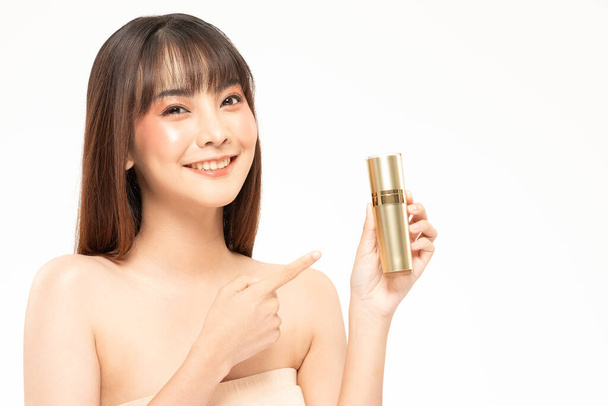 Beauté asiatique femme cheveux bruns regarder sourire à la caméra bonheur et tenir bouteille crème cosmétique lotion et gai avec pinceau de maquillage, Concept de beauté sur fond blanc. - Photo, image