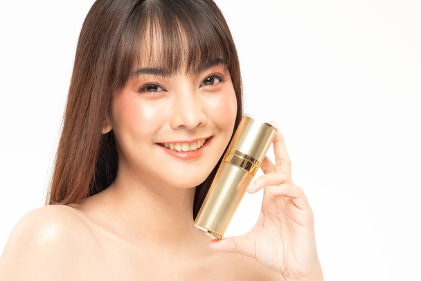 Beauté asiatique femme cheveux bruns regarder sourire à la caméra bonheur et tenir bouteille crème cosmétique lotion et gai avec pinceau de maquillage, Concept de beauté sur fond blanc. - Photo, image
