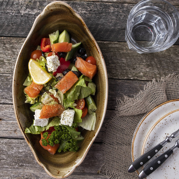 Salmon salad with fresh vegetables and black olives. Top view - Zdjęcie, obraz