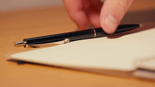 Селективный фокус человека, берущего ручку на стол возле ноутбука - Кадры, видео