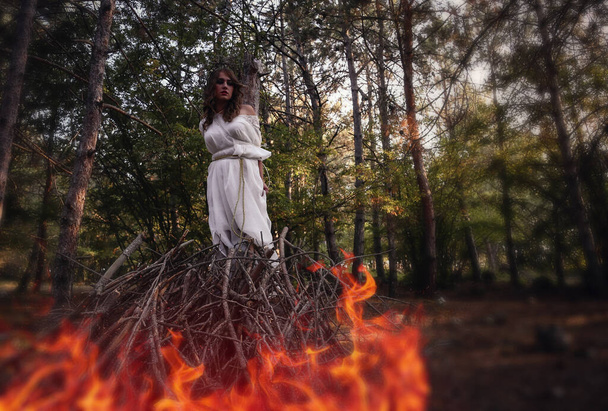 Belle femme gothique mystère en robe blanche longue dans la forêt d'automne. Sombre créature fantaisie, feu de joie pour une sorcière - Photo, image