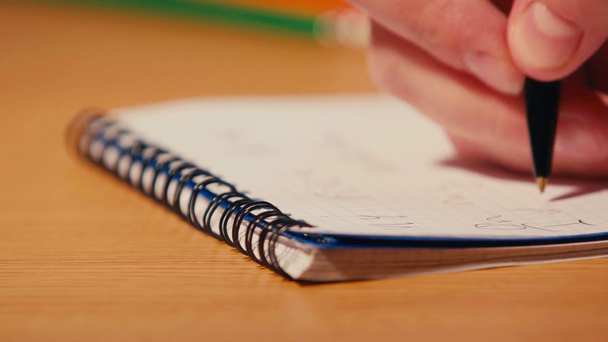 Foco cremalheira de homem escrevendo com caneta em caderno espiral - Filmagem, Vídeo