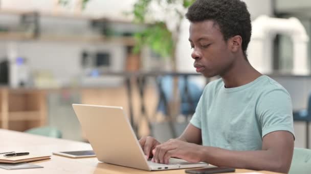 Nuori afrikkalainen mies kannettavan tietokoneen kanssa hymyilee kamerassa  - Materiaali, video