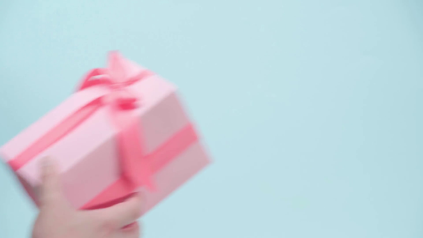 Rajatut näkymä mies antaa vaaleanpunainen lahjapaketti sinisellä pohjalla - Materiaali, video